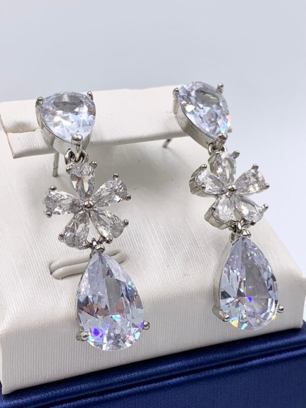 Aretes con piedra blanca y detalles dorados con piedritas blancas